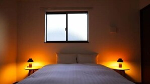 Een slaapkamer met een bed, twee bedlampen, een raam en een airconditioner aan de muur.