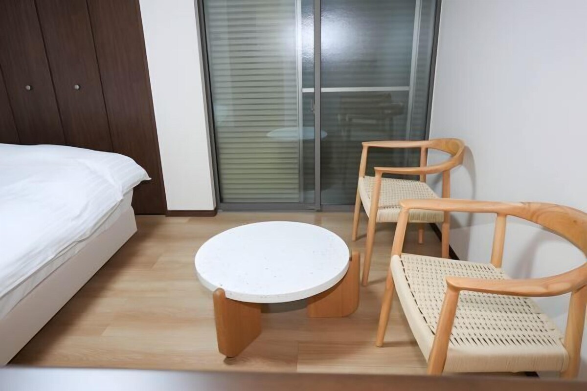 Une chambre à coucher avec un lit, une table ronde et deux chaises en bois.