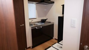 Een kleine keuken met een raam, een fornuis en een spoelbak.
