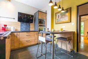 A modern kitchen with a bar area, wooden cabinets, and a painting on the wall.