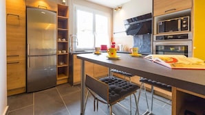 Eine moderne Küche mit Kühlschrank, Mikrowelle, Backofen und Barhocker.