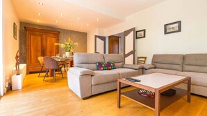 Ein Wohnzimmer mit einer Couch, einem Couchtisch, einem Esstisch mit Stühlen und einer Holzkabine.