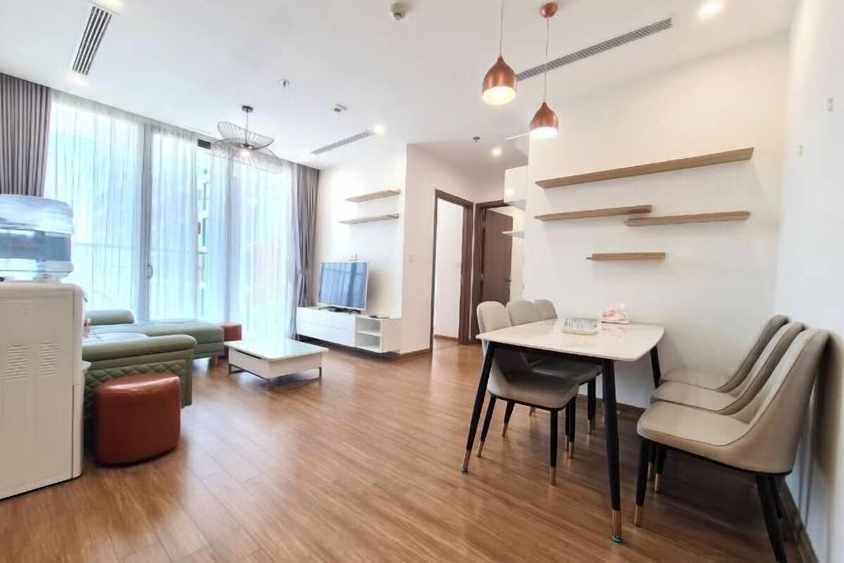 A modern living room with a sofa, a dining table, and a TV.