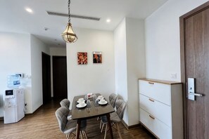Een eethoek met een tafel, stoelen, een waterdispenser en een koelkast.