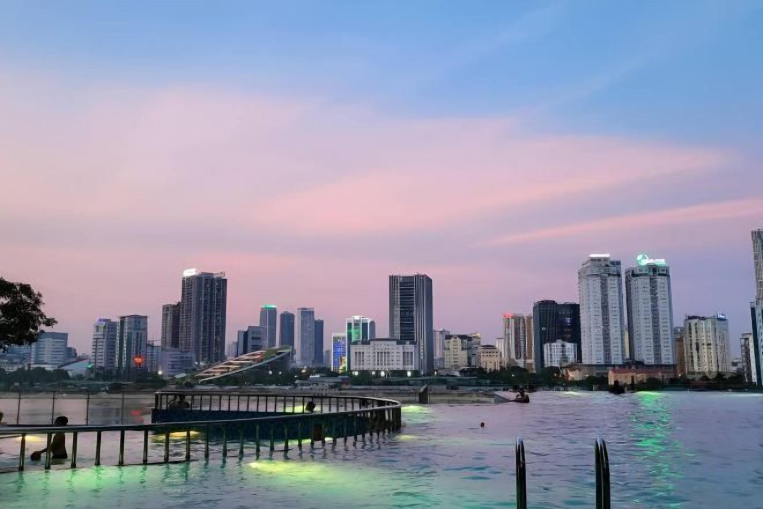 A city skyline with high-rise buildings and a waterfront promenade.