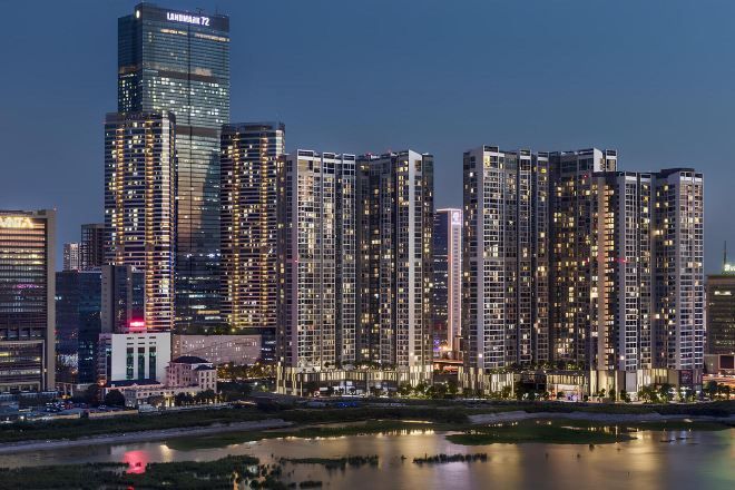 Une vue urbaine impressionnante, avec de hauts immeubles modernes, une rivière au premier plan et un ciel dégagé.