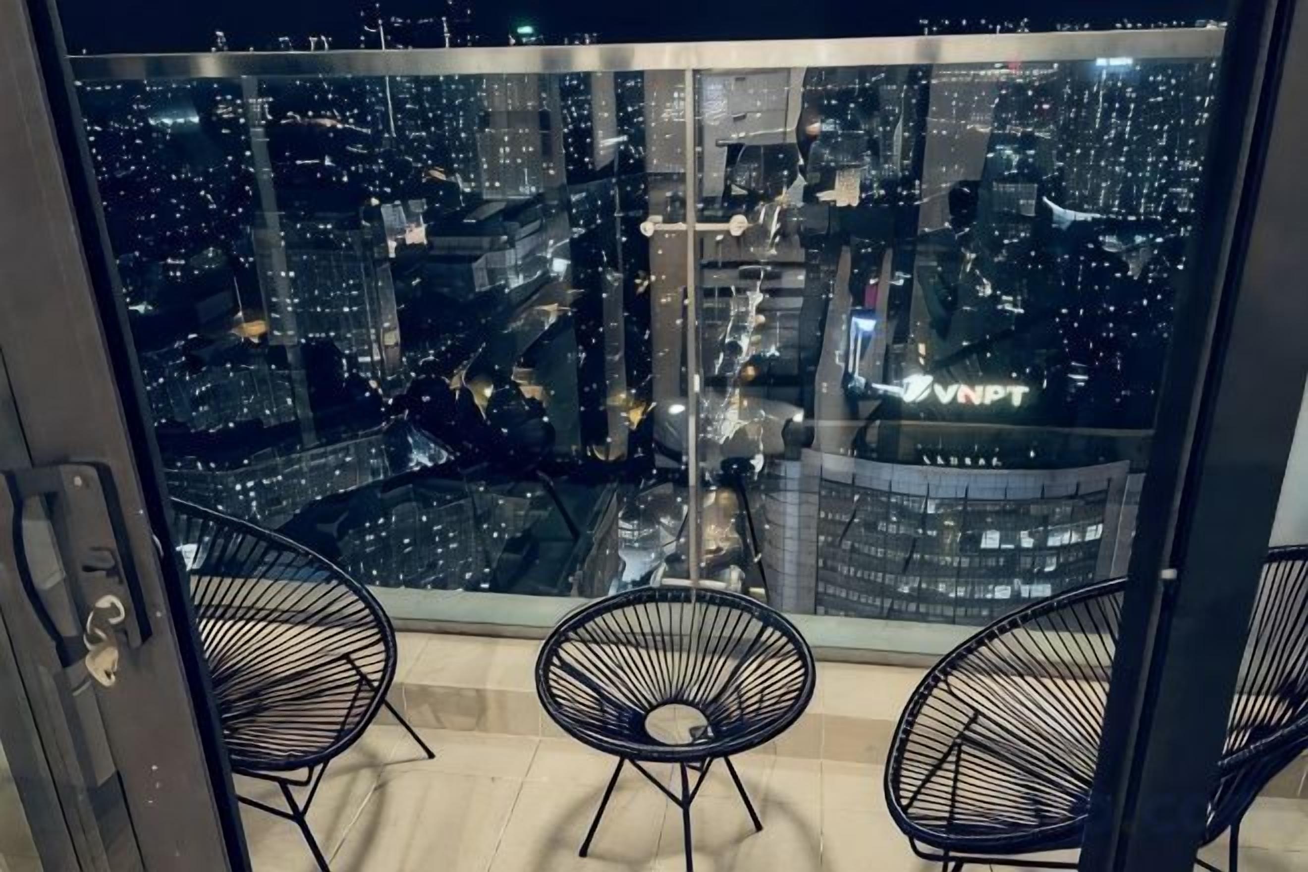 Un balcon avec deux chaises et une vue sur la ville de nuit.