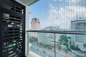 Un balcón con vista a un paisaje urbano, que incluye edificios y una carretera.