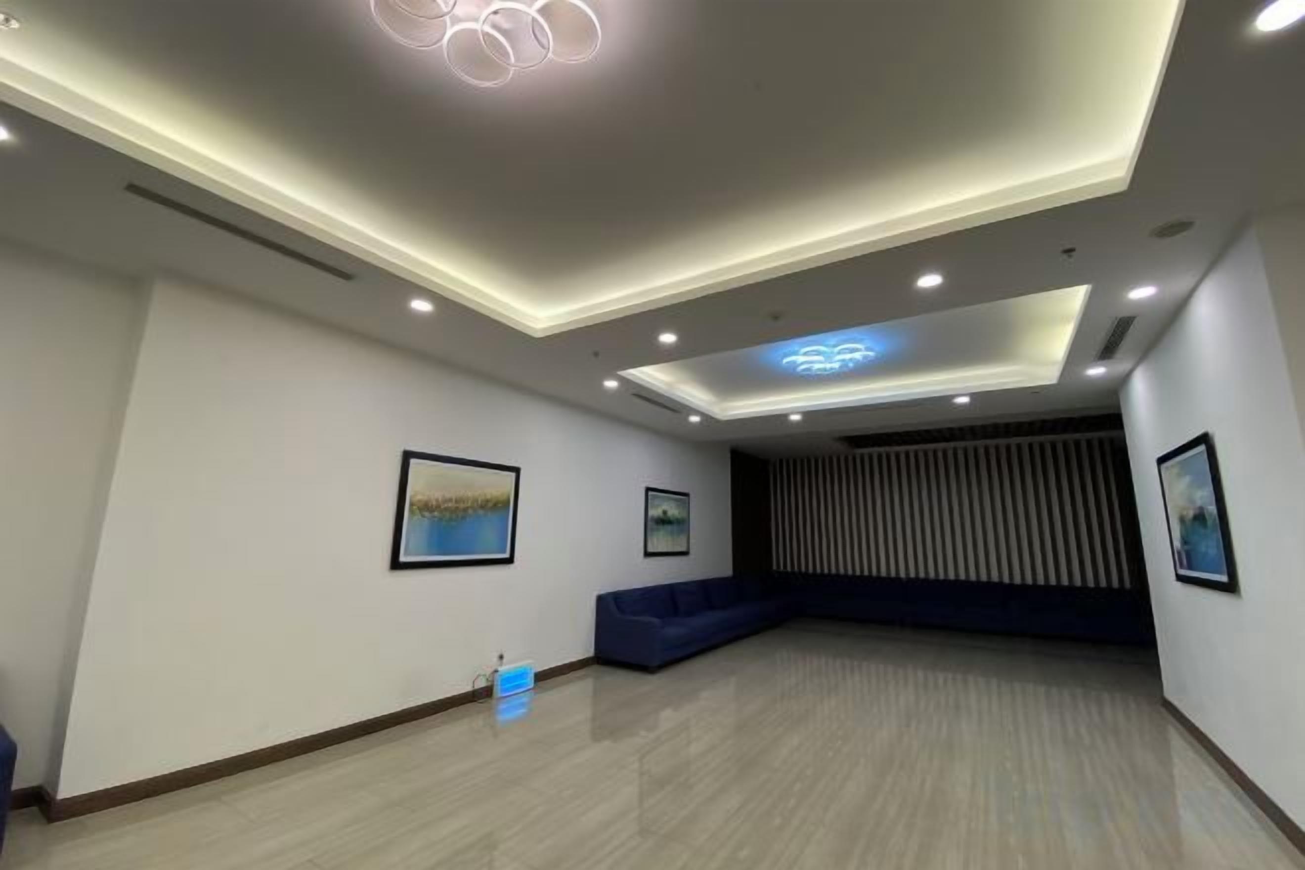 Une chambre d’hôtel moderne dotée d’un grand espace salon, d’un éclairage encastré au plafond et d’œuvres d’art encadrées qui ornent les murs.