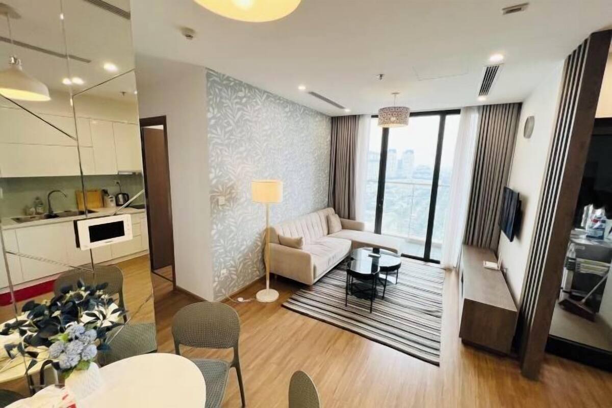 A modern hotel room with a sofa, dining table, and a view of the city.