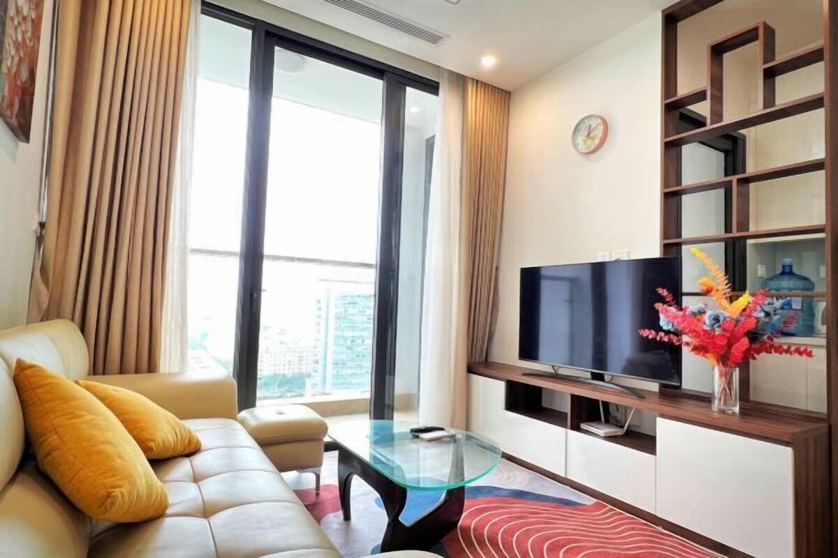 A modern living room with a sofa, glass coffee table, and a flat-screen TV.