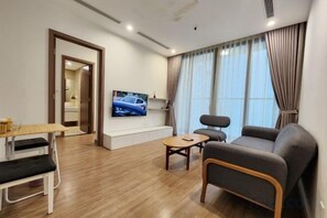 A modern living room with a sofa, a coffee table, and a TV mounted on the wall. - Vinhomes Skylake - Kane Shining Star Apartment in Ha Noi (Hanoi)