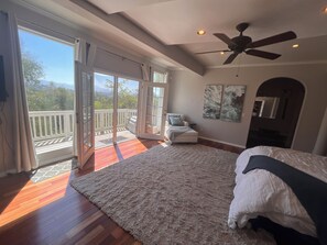 A bedroom with a large bed, a ceiling fan, and a view of the outdoors through a sliding glass door. - Spacious 5-bedroom house in lovely La Mesa with stunning views, lots of space (La Mesa)