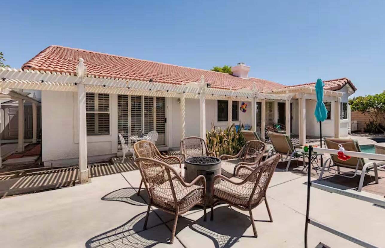 A covered patio with outdoor furniture, a fire pit, and a pool area.