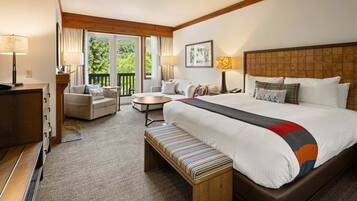 A hotel room with a bed, a sofa, a desk, a chair, a small table, and a bench.