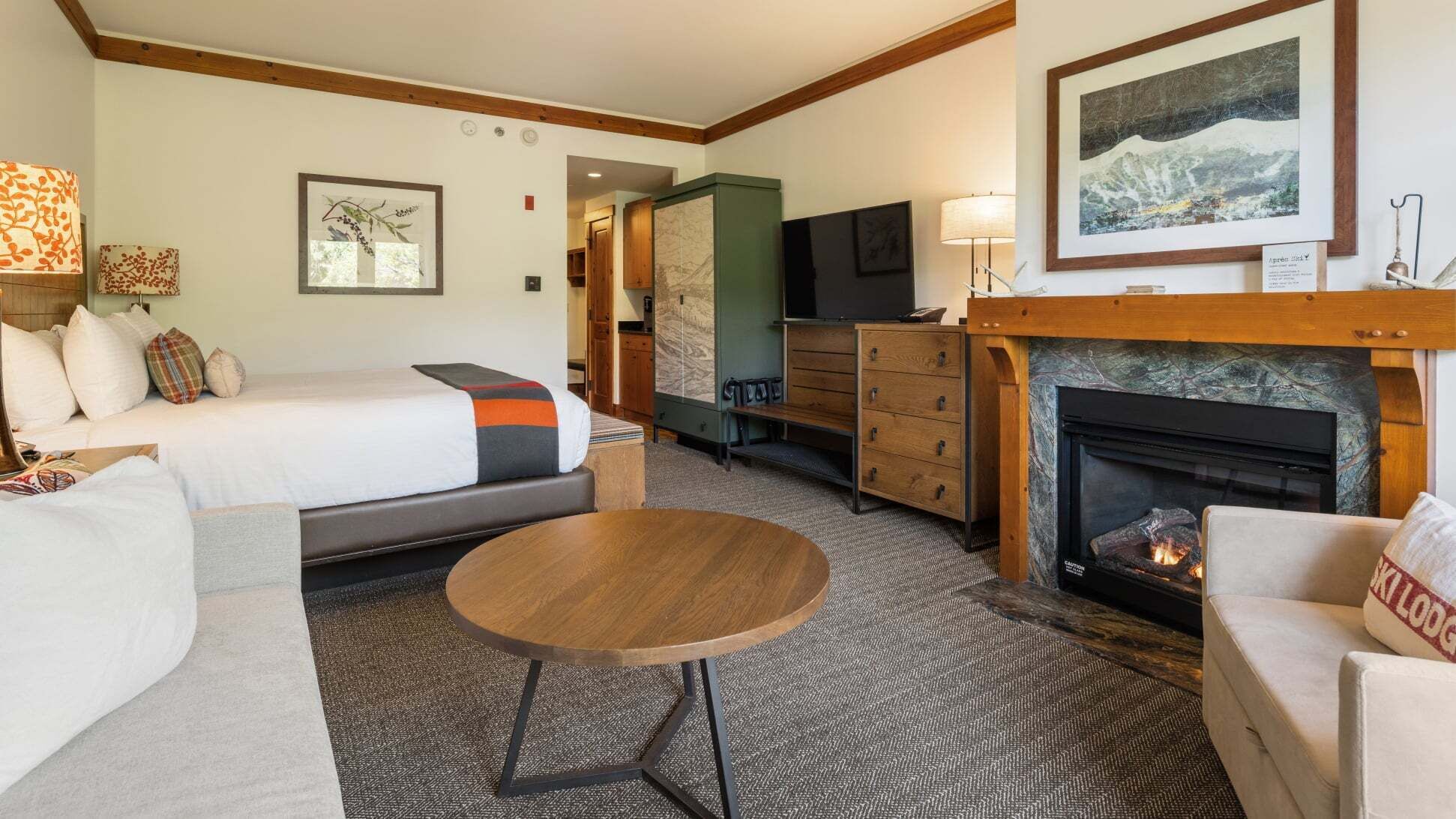 Een hotelkamer met een bed, een bank, een kleine tafel, een open haard en een televisie.