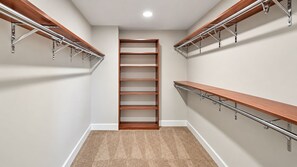 A walk-in closet with wooden shelving and metal racks, carpeted floor, and a white ceiling. - Spacious! Casino, R&R, Stadiums (Cleveland)