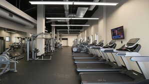 Ein modernes Fitnessstudio mit Laufbändern, Kraftgeräten und einem Fernseher an der Wand.