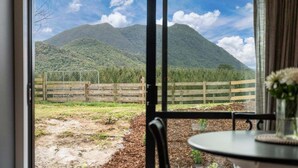 A room with a large window offering a view of a mountain and a wooden fence.