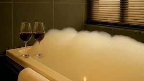 Una bañera con dos copas de vino tinto y dos velas encendidas.