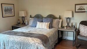 A bedroom with a bed, two nightstands, a chair, a ceiling fan, and two wall-mounted lamps.