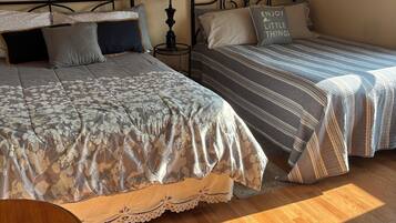 A bedroom with two beds, a small table, and a painting on the wall.