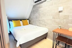 A bedroom with a bed, a small table, and a chair.