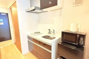 A compact kitchen with a microwave, sink, and cabinets.