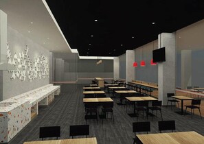A modern classroom with rows of desks and chairs, a long bench along the wall, and a flat-screen TV mounted on the wall. - Amaris Hotel Manado (Wenang)