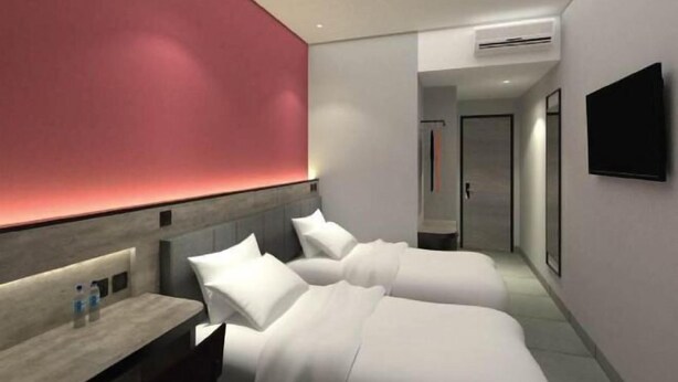 A modern hotel room with a bed, bedside table, and a TV mounted on the wall. - Amaris Hotel Manado (Wenang)