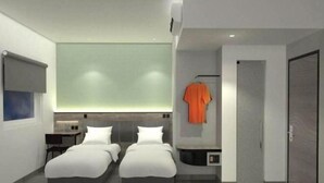 A modern hotel room with two beds, a small desk, a wardrobe, and a large window. - Amaris Hotel Manado (Wenang)