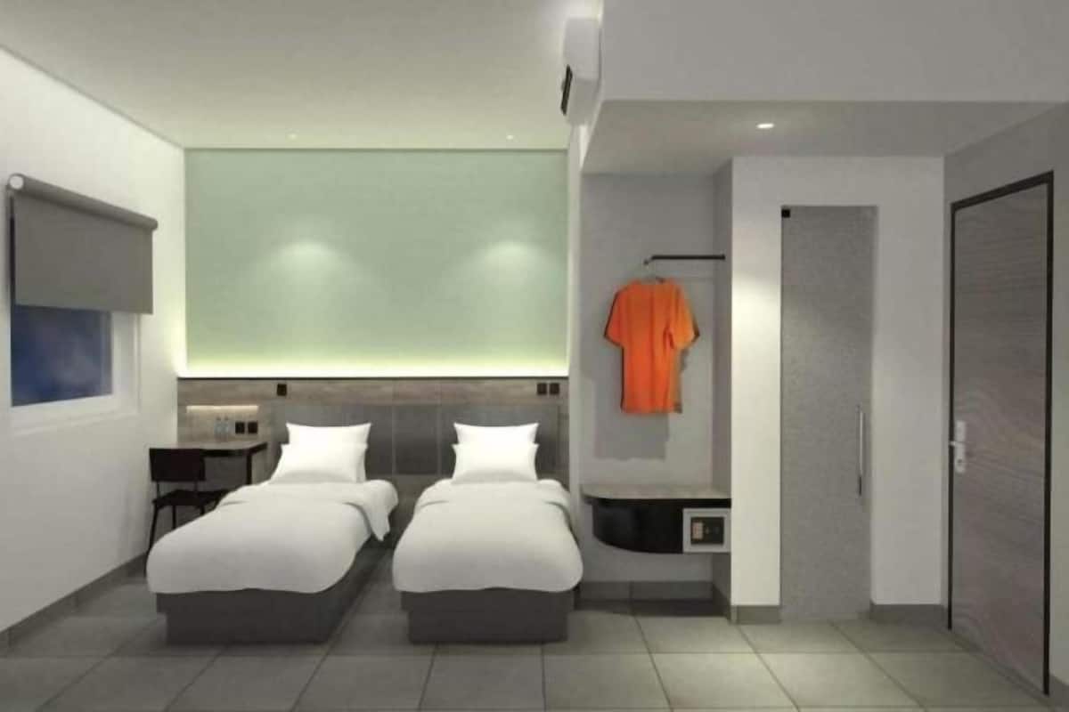 A modern hotel room with two beds, a small desk, a wardrobe, and a large window.