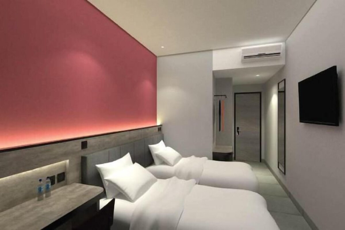 A modern hotel room with a bed, bedside table, and a TV mounted on the wall.