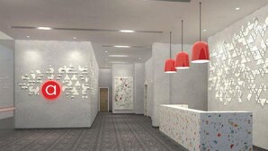A modern reception area with a geometric wall design, a prominent 'a' logo, and a reception desk with a colorful speckled pattern. - Amaris Hotel Manado (Wenang)