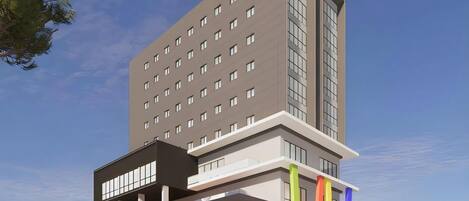 A modern hotel building with multiple floors, a prominent sign at the top, and a ground-level entrance with a visible sign.