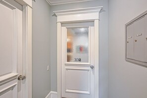 Una puerta blanca con paneles de vidrio esmerilado y una placa con el número 102.