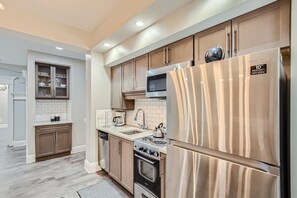 Una cocina moderna con electrodomésticos de acero inoxidable, armarios de madera y un salpicadero de azulejos.