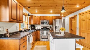 A modern kitchen with wooden cabinets, stainless steel appliances, and a central island.