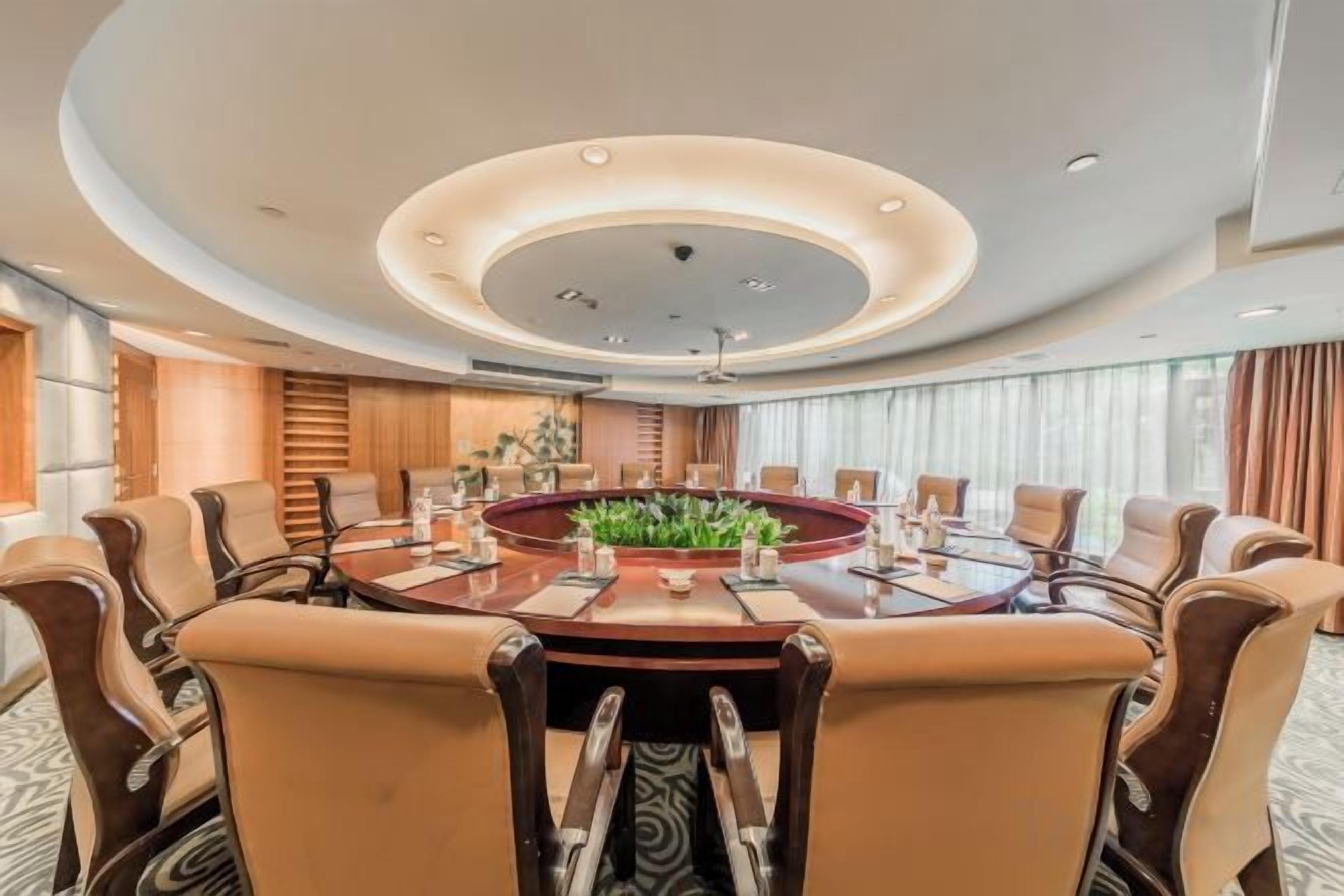 A conference room with a round table, multiple chairs, and a ceiling light fixture.