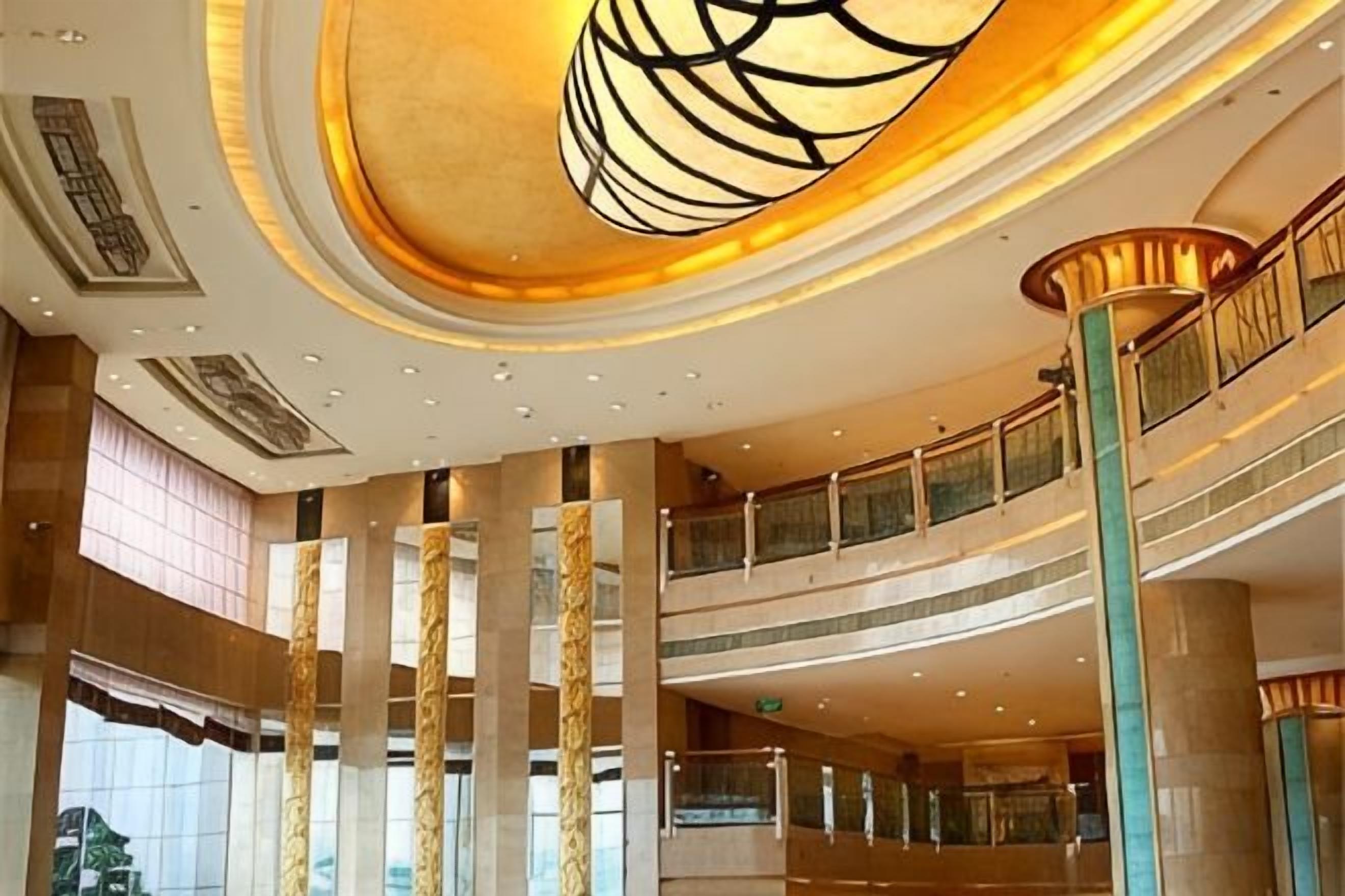A multi-level atrium with a grand staircase, large columns, and a modern chandelier.