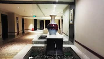 Un couloir agrémenté d’une fontaine décorative, d’un vase et d’un sol à motifs.