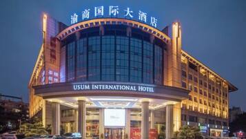 Un hotel con fachada moderna, amplias ventanas de vidrio y señalización destacada que indica que se trata del HOTEL USUM INTERNATIONAL.