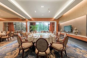 Un salón de conferencias con una mesa redonda, sillas y un televisor en la pared.