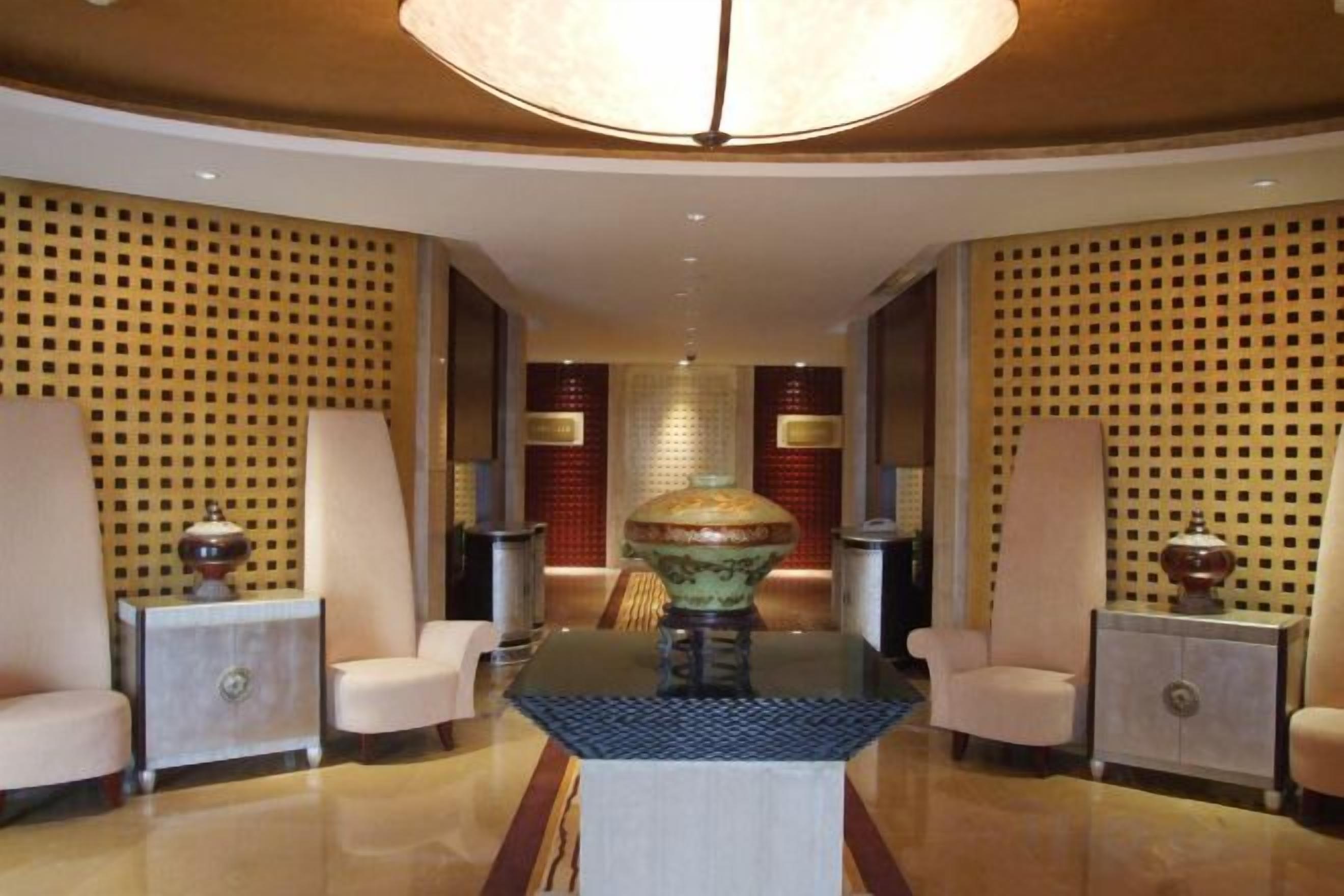 A lobby with a central table, two side tables, and a chandelier.
