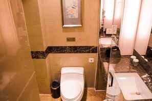 A compact bathroom with a toilet, sink, and trash bin. - USUM International Hotel (Chongqing)