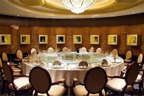 Un salón de conferencias con una mesa redonda, sillas y una araña.