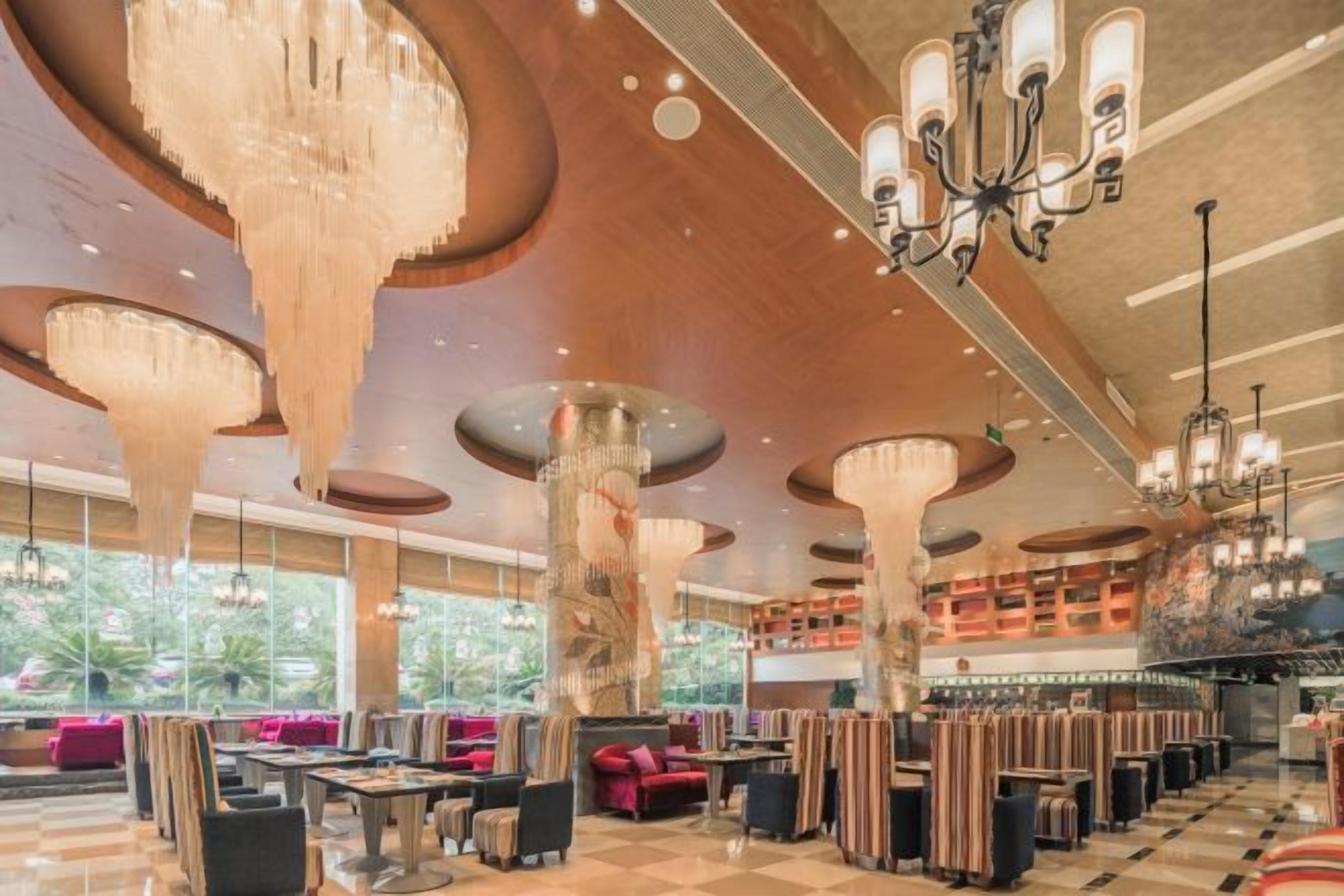 A spacious lobby with high ceilings, large chandeliers, and a checkered floor pattern.