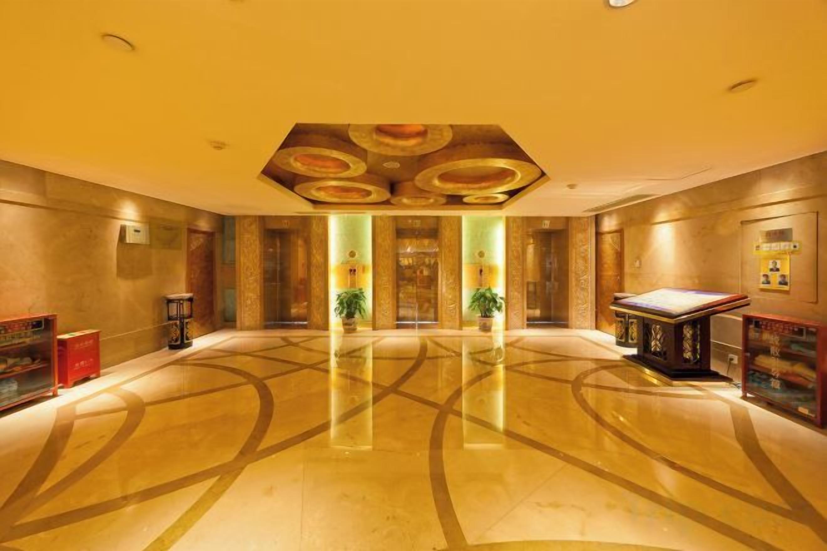 Um hall espaçoso com piso lustroso, um balcão de recepção e uma parede grande com padrão geométrico.