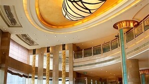 En flerplans atrium med en central søjle, gelændere og en stor lysekrone.