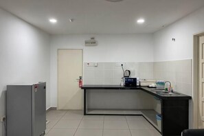 Una cocina pequeña con refrigerador, lavamanos y encimera.